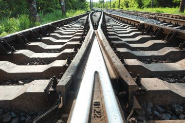 Demiryolu devreleri ve geometrik yapılar, eşikler, çakıllar ve vidalar ile kesişen raylar. Simetrik ray indirmeleri yansıtılıyor