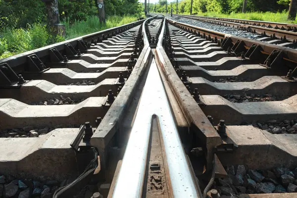 Demiryolu devreleri ve geometrik yapılar, eşikler, çakıllar ve vidalar ile kesişen raylar. Simetrik ray indirmeleri yansıtılıyor
