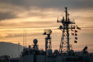 Parabolik uydu antenleri ve karmaşık metal yapılar, gri bulutlu gökyüzüne karşı kurulmuş bir iletişim kulesinin parçası.