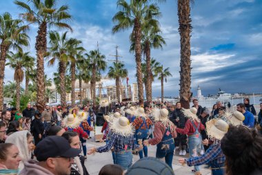 Dans gösterisi ya da sosyal dans toplantısı gibi görünen bir grupla açık hava sahnesi. Genellikle geleneksel veya geleneksel olarak kullanılan büyük hasır şapkalar giyiyorlar.