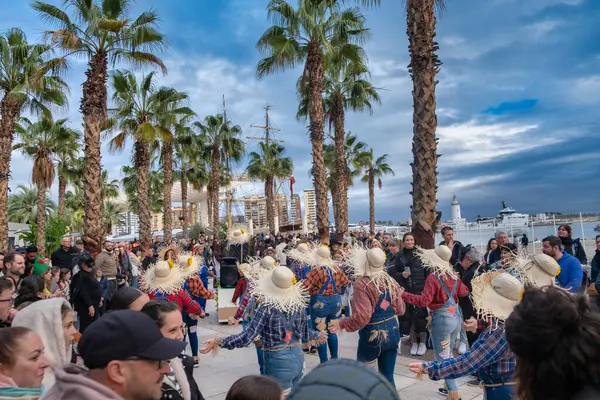 Stock image outdoor scene with a group of people engaged in what appears to be a dance performance or social dance gathering. They are wearing large straw hats, which are often associated with traditional or