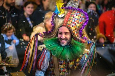 Canlı kostümlü, geometrik başlıklı, neşeli izleyiciler arasında konfeti dolu karnavalın tadını çıkaran şenlikli bir kutlama. Yüksek kalite fotoğraf