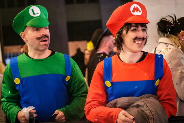 Mario video oyunu serisiyle ilişkili karakterler gibi giyinmiş iki kişi. Solda, biri yeşil tişört, mavi tulum, yeşil şapka ve sahte bir 