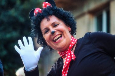 Görüntü, Minnie Mouse 'a benzeyen bir kostüm giymiş birini gösteriyor, tanınmış bir animasyon karakteri. Kişi siyah bir üst, benekli kırmızı bir kafa bandı, fare kulakları ve kırmızı bir fiyonk takıyor.