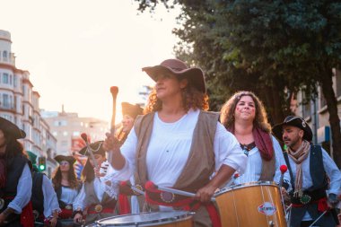 Görüntü, sokak geçidi veya festivaline katılan bir grup insanı yakalıyor. Tarihsel ya da kültürel görünümleri olan kostümler giyiyorlar.