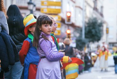 Çeşitli çocuklar geçit töreninde, birinde gökkuşağı bayrağı var. Şehir caddesinde canlı kıyafetler giyip kapsayıcılığın sinyalini veriyorlar. Gün batımında olay arkaplanı.