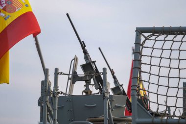 Ağır makineli tüfekler, güvenlik bariyerleri ve deniz savunma bağlamını simgeleyen görünür İspanyol bayrağı içeren İspanyol askeri gemisi kurulumu