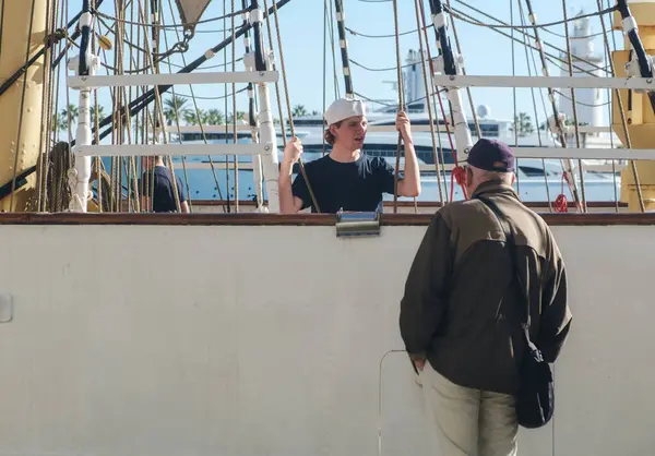 İki arkadaş, güneşli bir güvertede, deniz manzaralı bir fotoğrafın ortasında derin bir sohbete girişiyor.