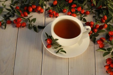 Cup of tea with rose berries on a white wooden background