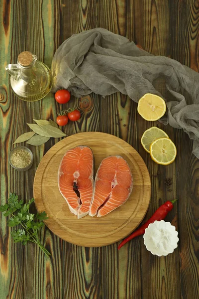 Fresh salmon steak with ingredients on dark wooden background