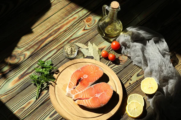 Fresh salmon steak with ingredients on dark wooden background