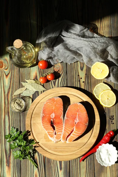 Fresh salmon steak with ingredients on dark wooden background