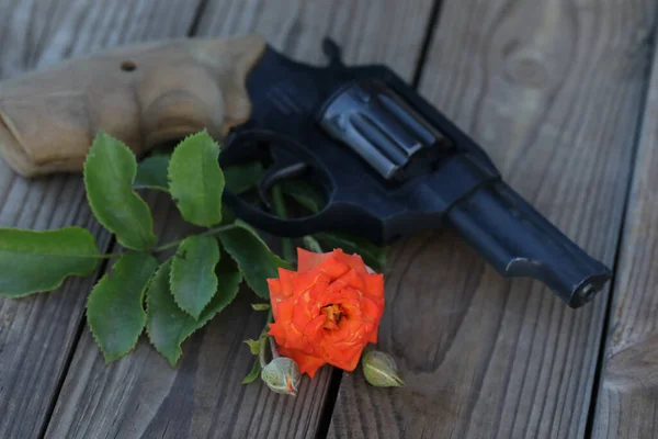 art photo. vintage still life with gun and rose on wooden background 