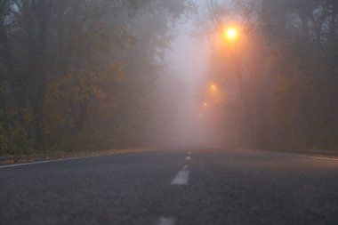 empty asphalt road with a fog and yellow street lights 