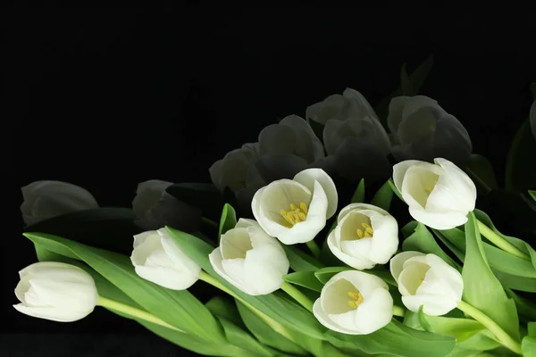 Beautiful bouquet of white tulip flowers with card on black background, space for text