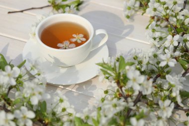 Beyaz ahşap arka planda kiraz çiçeği süslemeli çay..