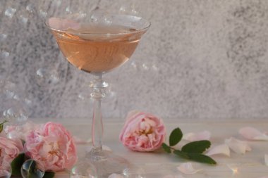 Açık gri zemin üzerinde gül çiçekleri olan pembe şampanya.