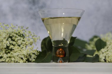 Ahşap arka planda yaşlı çiçeklerin süslendiği yaşlı çiçek likörlü orijinal cam.