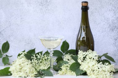 Elderflower likörüyle birlikte bardak ve bir şişe şampanya. Açık gri arkaplanda kopyalama alanı