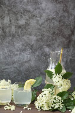 Yaşlı çiçeklerle dolu bir şişe limonata. Açık gri arkaplanda kopyalama alanı