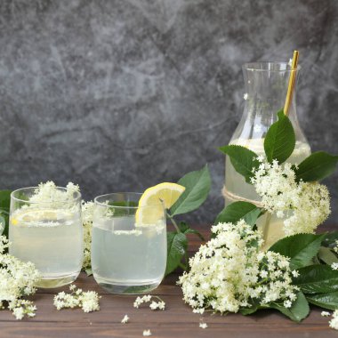 Yaşlı çiçeklerle dolu bir şişe limonata. Açık gri arkaplanda kopyalama alanı