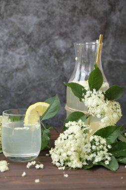 Yaşlı çiçeklerle dolu bir şişe limonata. Açık gri arkaplanda kopyalama alanı
