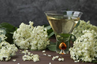 Ahşap arka planda yaşlı çiçeklerin süslendiği yaşlı çiçek likörlü orijinal cam.