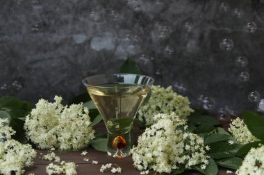 Ahşap arka planda yaşlı çiçeklerin süslendiği yaşlı çiçek likörlü orijinal cam.