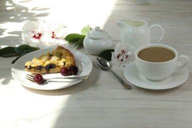 Kirazlı lezzetli Quiche turtası beyaz tabakta bir fincan kahveyle doluyor. Beyaz tahta arkaplan