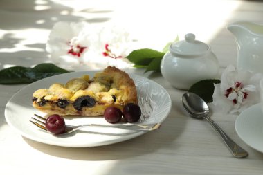 Kirazlı lezzetli Quiche turtası beyaz tabakta bir fincan kahveyle doluyor. Beyaz tahta arkaplan
