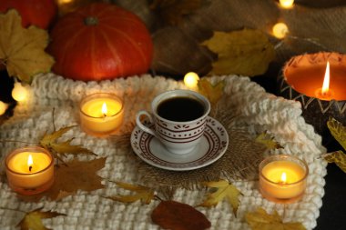 Sonbahar arka planında yapraklı ve mumlu bir fincan kahve.