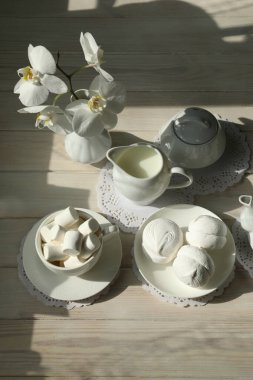 Marşmelov, kahve ve sütle bahar kahvaltısı. Beyaz renkli yiyecek ve çiçeklerle bembeyaz düzlük