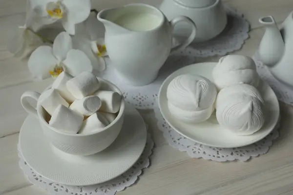 Spring breakfast with marshmallow, coffee and milk. Flatlay with food and flower in white color