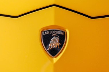 İstanbul, Türkiye - 9 Ağustos 2023: Lamborghini metalik logosu. Sarı Lamborghini Huracan 'ın önü. İtalyan markası ve lüks spor araba üreticisi. 