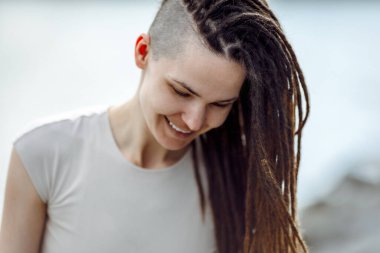 Güneşli bir günde rastalı saçlı güzel bir kız. Milenyum ve hippilerin trendi