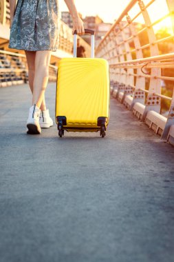 Sarı bir bavul taşıyan bir kadın şehirde dolaşıyor. Seyahat eden turist