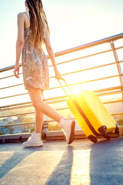 Sarı bir bavul taşıyan bir kadın şehirde dolaşıyor. Seyahat eden turist