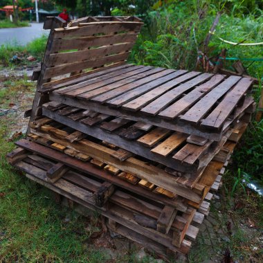 Yığılmış ahşap paletler yol kenarındaki çimlerde.