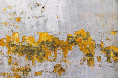 Yıpranmış beton duvar, sarı boya soyulmuş ve şehir merkezinde çatlaklar var..