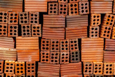 Çeşitli desenlerde ve renklerde delikleri olan kırmızı tuğlalar yığıldı.