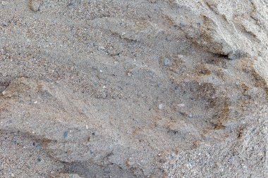 Küçük çakıl taşlarıyla desenli kumlu yüzeye yakın çekim.