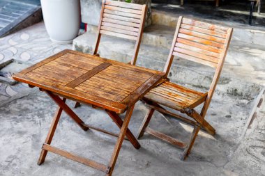 Kırsal ahşap açık masa ve beton verandada sandalyeler..