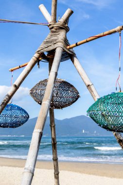 Geleneksel bambu balığı tuzağı kumlu sahilde, arkasında okyanus ve dağlar olan..