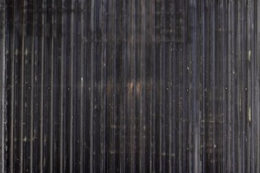 Dikey oyukları ve yıpranmış dokusu olan paslı metal bir yüzey..