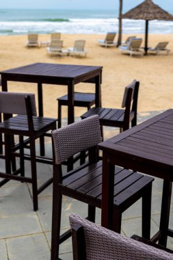 Deniz kenarında boş sandalyeleri ve masaları olan tropik bir sahil barı..