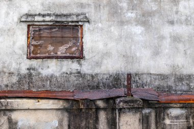 Paslı parmaklıklı yıpranmış duvar ve şehir ortamında küçük pencere.