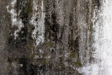 Grungy weathered concrete wall with dark mold and textured surfaces. clipart