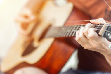 Genç beyaz erkek akustik gitar çalıyor. Yakın plan..