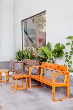 Açık şehir avlusunda yeşillikli ahşap bank ve masa..