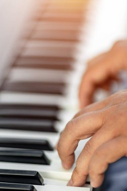 Parmak ve müzikal ifade odaklı piyano tuşları çalan ellerin yakın çekimi.